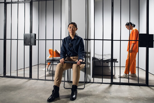 A typical day in a women's prison. A bored female guard in uniform sits near the cells with female prisoners