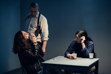 A suspect in a police station laughs madly during an interrogation conducted by investigators.