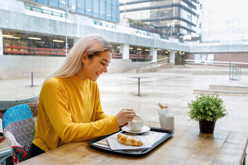 Happy young woman having breakfast at cafe during rainy season