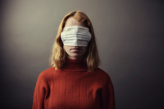 Teenage girl wearing protective face mask on eyes while standing against gray background