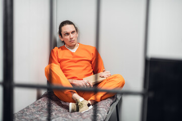 A young inmate with a tattooed face is being remotely trained in a cell. Reads a textbook sitting...
