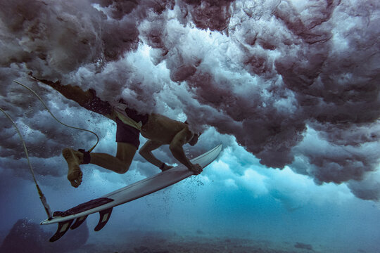 Male surfer on surfboard diving undersea at Maldives