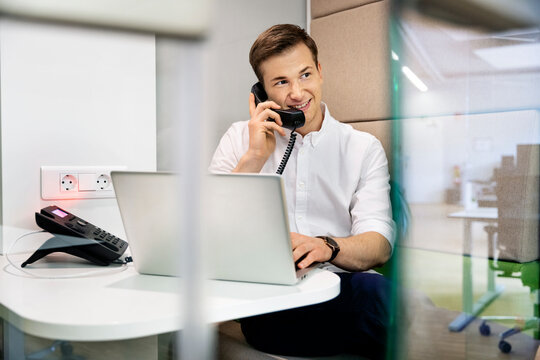 Businessman smiling while talking on telephone sitting at office