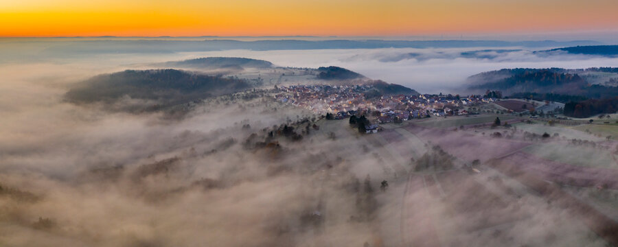 Germany, Baden-Wurttemberg, Berglen, Drone view of village shrouded in thick fog at dawn