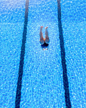 Young woman diving into swimming pool on sunny day