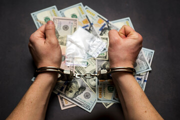 Man in handcuffs with money and drugs on dark background. The concept of punishment for possession, distribution and use of drugs.  Concept no to drugs