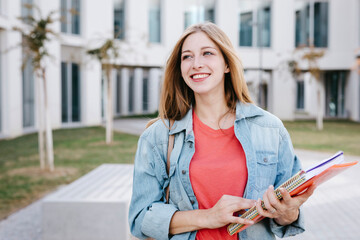 Happy young female Caucasian student looking away at university campus