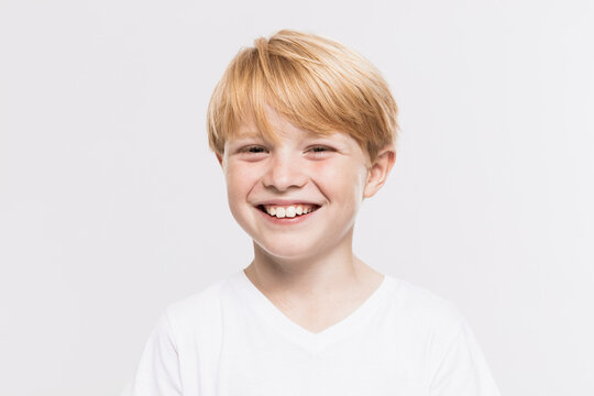 Cheerful Cute Boy With Blond Hair Against White Background