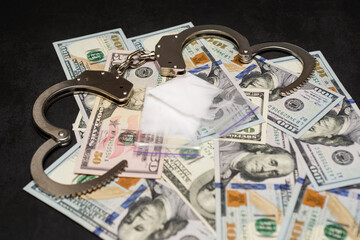 Money, drugs and handcuffs. Handcuffs, money and cocaine drugs on dark background close up