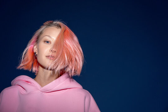 Portrait of young woman with pink hair wearing pink hooded shirt at dusk