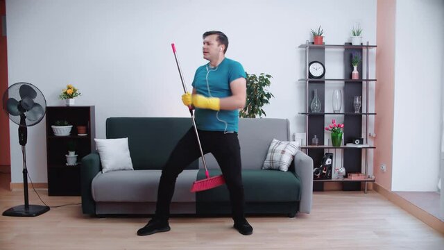 A cleaning man with headphones dances and sings.