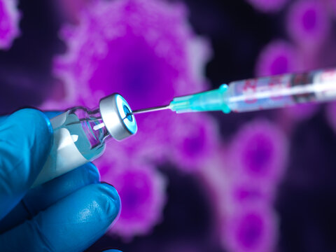 Hand in surgical glove holding vaccine for global pandemic