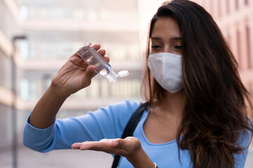 Businesswoman in face mask pouring sanitizer on hand during COVID-19