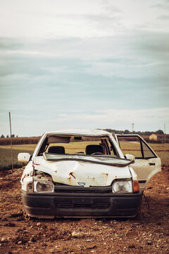 White wrecked car abandoned in middle of field