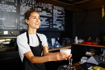 Smiling female barista giving coffee at cafe