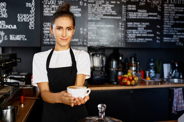 Portrait of smiling waitress giving coffee at cafe