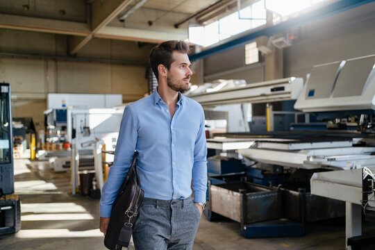 Male entrepreneur with brief case walking at factory
