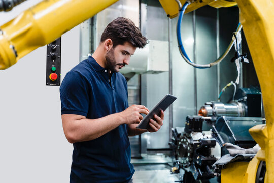 Male worker using digital tablet while standing in factory
