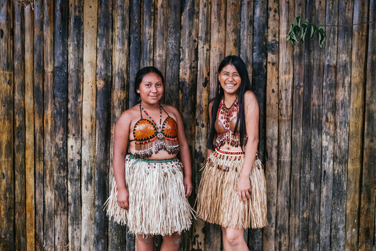 Smiling Guarani tribal females standing against bamboo wall at Misahualli, Ecuador