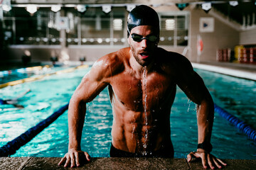 Professional muscular male swimmer getting out of pool