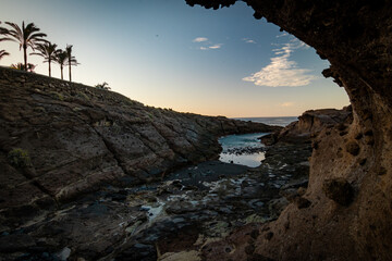 Sunset light over wave splashing on rocky volcanic stones, Tenerife, Canary islands, Spain