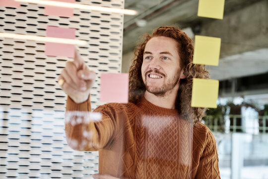Smiling man pointing on adhesive note stick on glass material at home