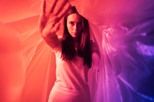 Young woman doing stop gesture while covered in plastic during coronavirus