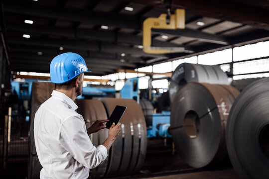 Male entrepreneur holding digital tablet while standing in industry