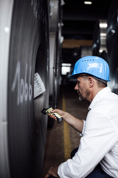 Businessman scanning barcode on steel rolls while standing in industry