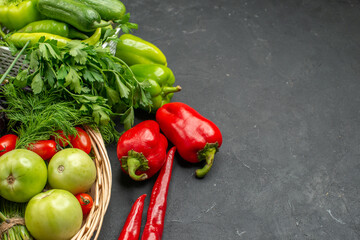 Vegetable basket with a bunch of green and peppers cucumber and tomatoes with stem on dark background image