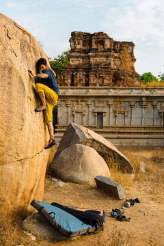 Man climbing rock at Hampi, Karnataka, India during sunset