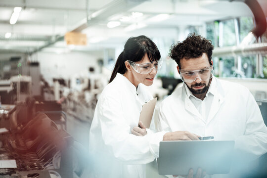 Male and female scientists discussing over laptop at laboratory