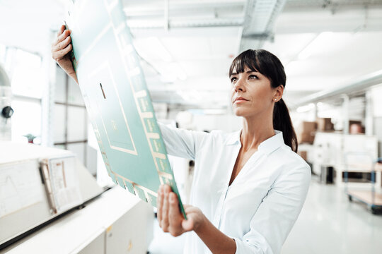 Confident female technician analyzing large computer chip in industry