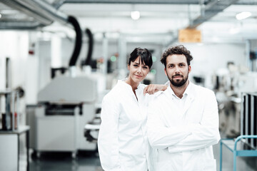 Male and female scientists in white lab coats standing at bright laboratory