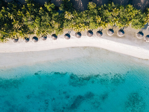 Maldives, Kaafu Atoll, Hudhuranfushi, Aerial view of row of huts along sandy coastal beach of Hudhuranfushi island