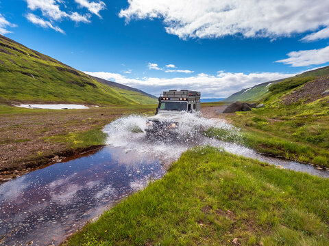 Off-road car crossing river on way to Drangajokull glacier