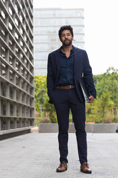 Entrepreneur with hand in pocket holding folder in city