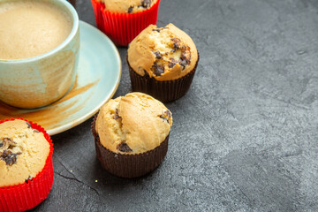 Half shot of delicious coffee around small cupcakes on dark background