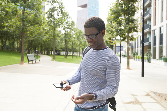 Businessman Untangling In-ear Headphones In Downtown On Sunny Day