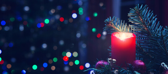 Christmas red candle with decorations and fir tree isolated on lights background.