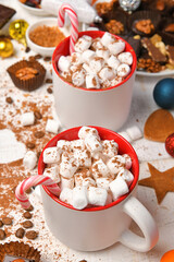 sweet food top view background for merry christmas or new year holiday decoration - chocolate candies, tangerines, cookies, marshmallow and cocoa latte on white wood