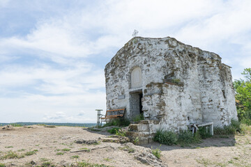 Old remote small stone chapel in Bulgaria. Historical ancient church in ruins with bench and cross. Cultural catholicism and holy sanctuary on a peaceful place