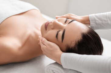 Young asian woman relaxing during face massage session at beauty spa salon