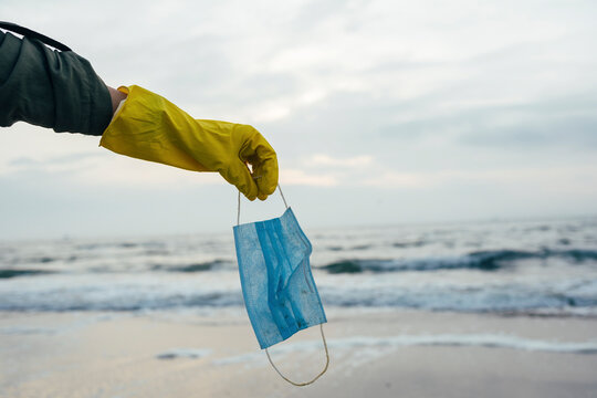 Woman holding face mask against beach - Powered by Adobe