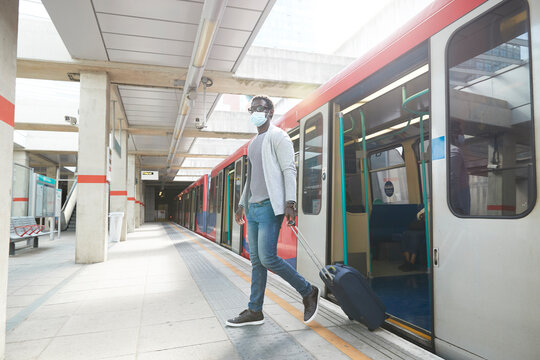 Male entrepreneur business travel disembarking metro train at station during pandemic