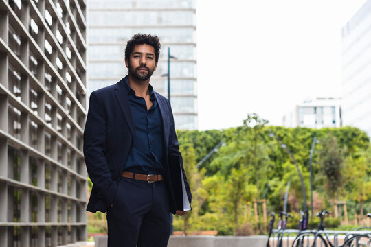 Male entrepreneur with hand in pocket holding folder in city