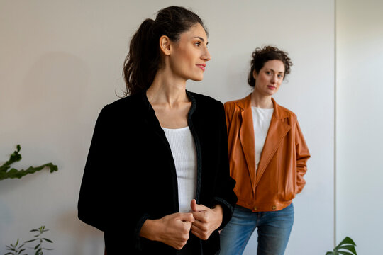 Female models wearing jacket standing against wall at home