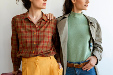 Female friends wearing retro style clothing standing against wall