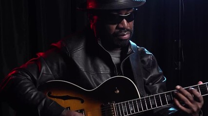 Close up Black Jazz musician soulfully playing guitar in dark studio - Powered by Adobe