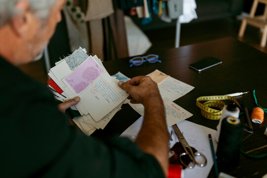 Mature male tailor looking at fabric swatch in work studio
